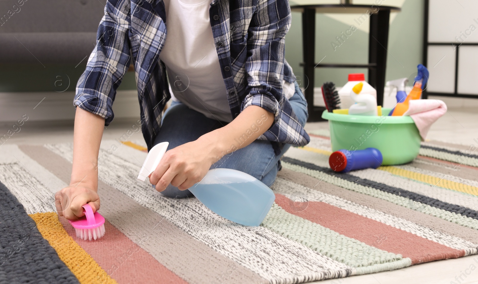 Photo of Woman cleaning carpet with brush at home