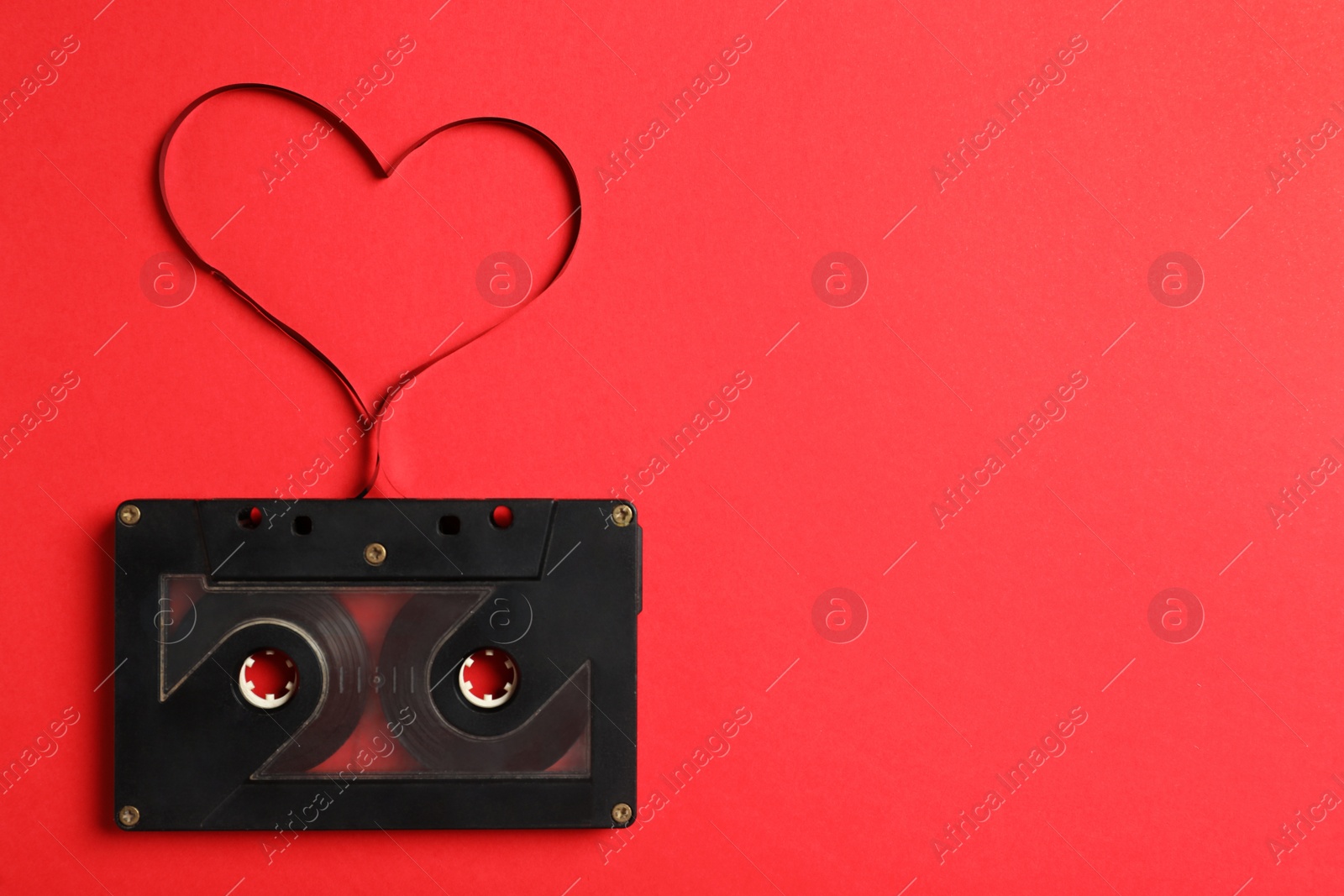 Photo of Top view of music cassette and heart made with tape on red background, space for text. Listening love song