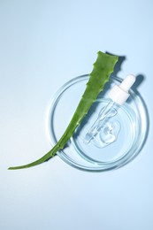 Petri dishes with cosmetic gel and aloe vera leaf on light blue background, top view