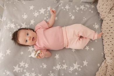 Photo of Time to sleep. Cute little baby with bunny toy lying in crib, top view