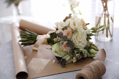 Beautiful wedding bouquet and paper sheet at light grey marble table, closeup