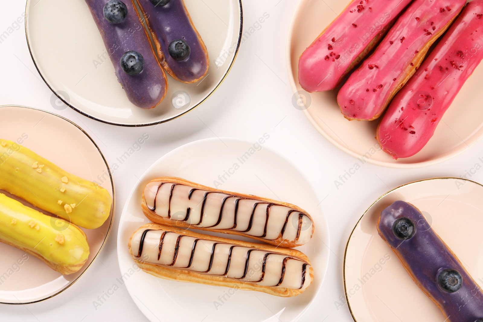 Photo of Delicious eclairs covered with glaze on white background, top view