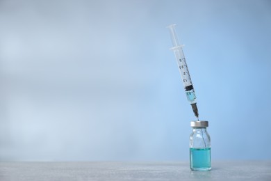 Syringe and vial on light grey table. Space for text