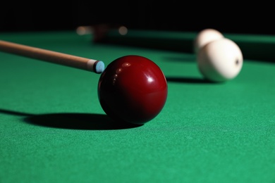 Photo of Striking red billiard ball with cue on table