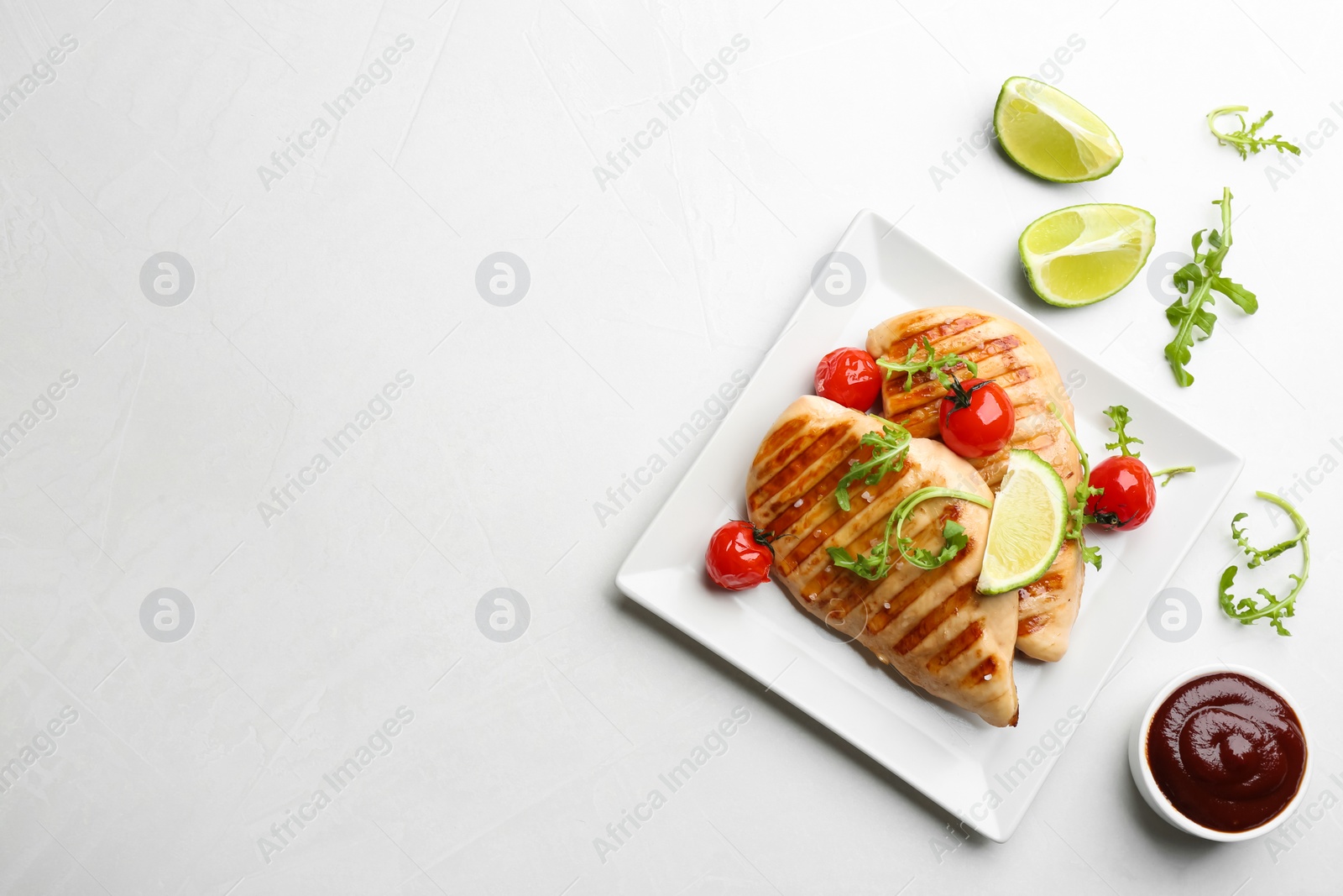 Photo of Tasty grilled chicken fillets with cherry tomatoes and lime slices on light grey table, flat lay. Space for text