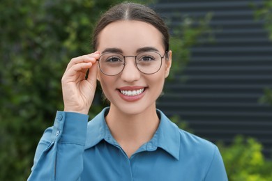 Photo of Portrait of beautiful woman in glasses outdoors. Attractive lady smiling and looking into camera