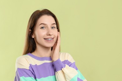Portrait of smiling woman with dental braces on light green background. Space for text
