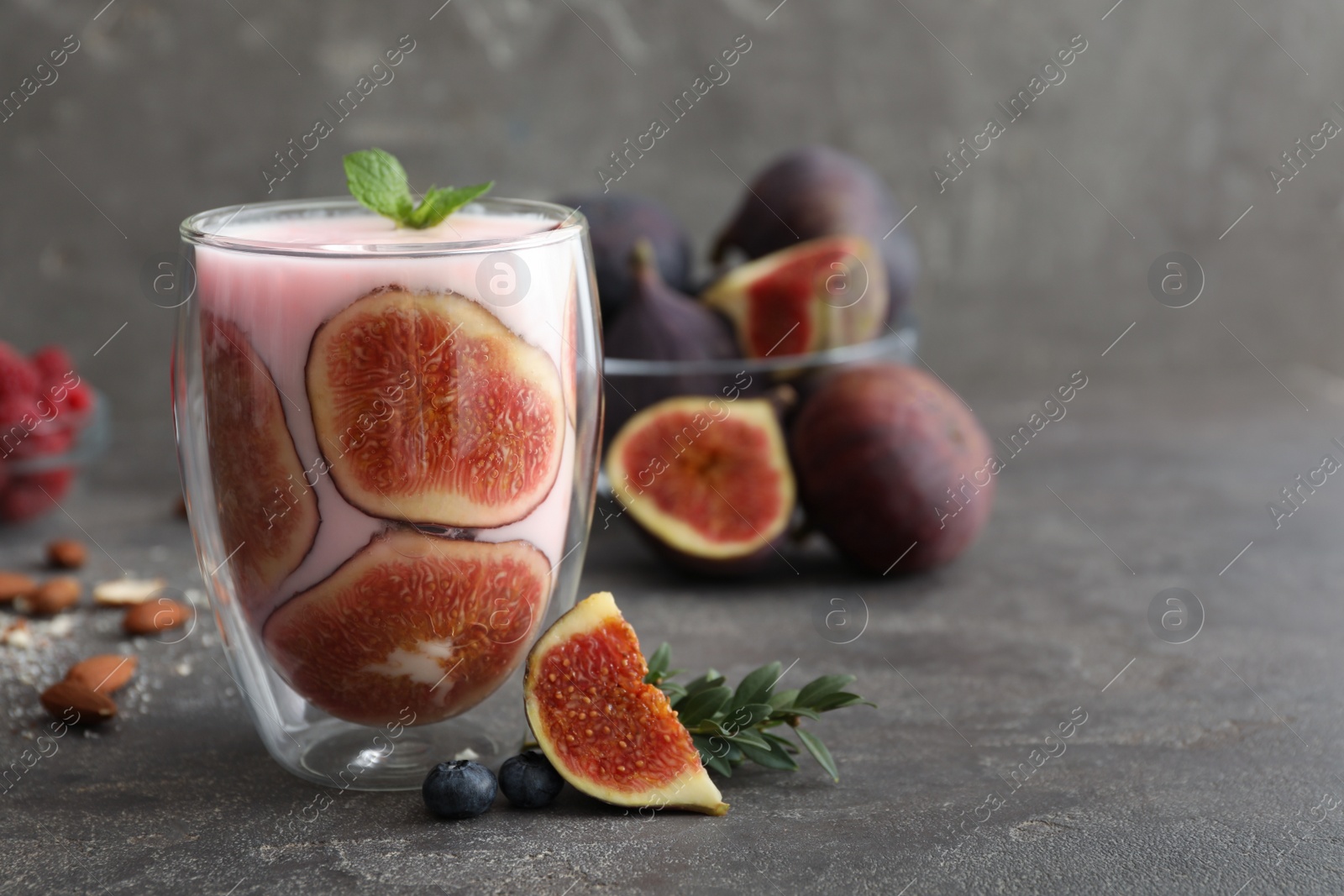 Photo of Delicious fig smoothie in glass on grey table, space for text
