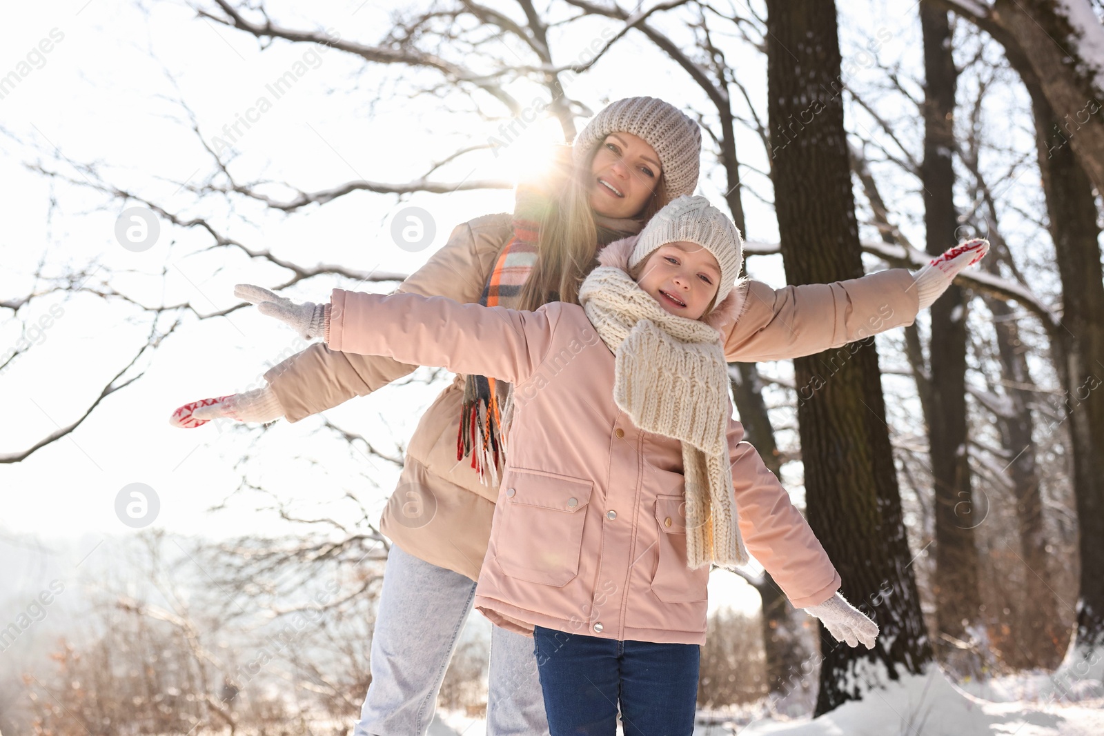 Photo of Family portrait of happy mother and her daughter in sunny snowy forest