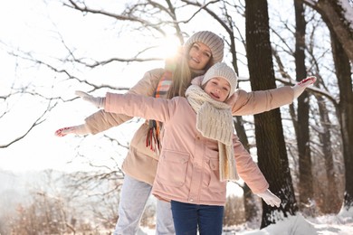 Photo of Family portrait of happy mother and her daughter in sunny snowy forest