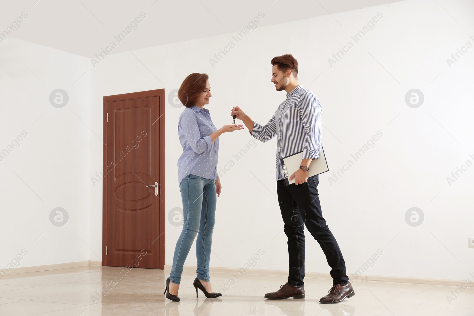 Photo of Real estate agent giving apartment keys to client indoors