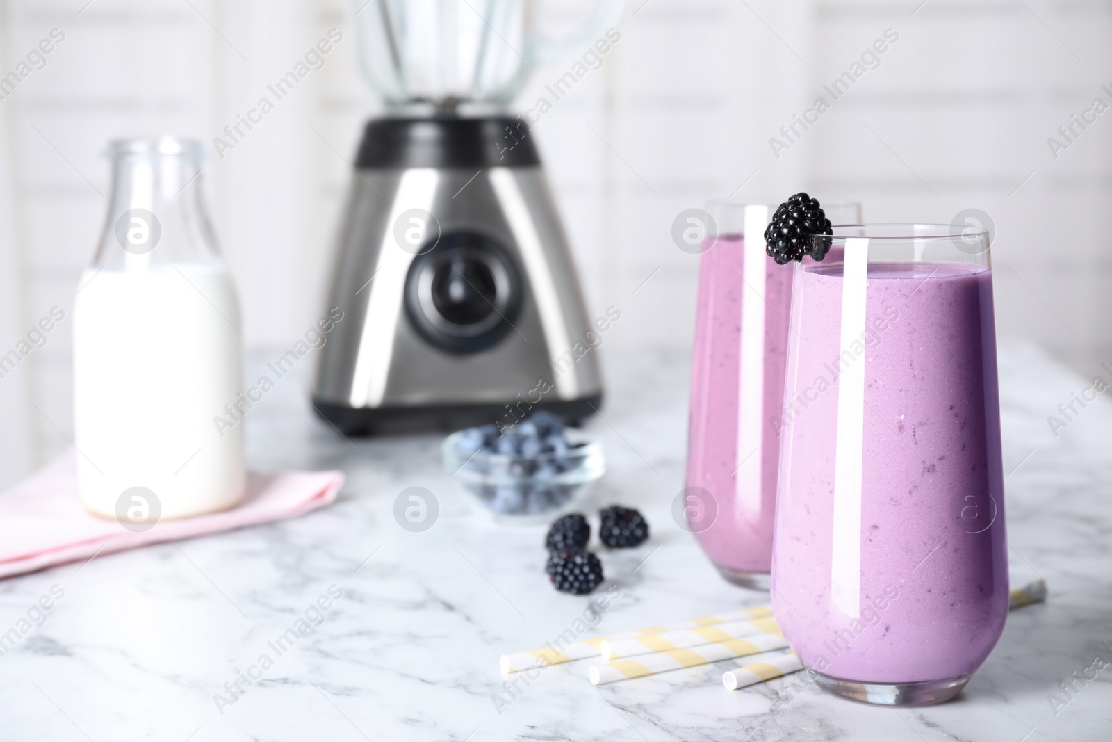 Photo of Tasty milk shakes and berries on white marble table