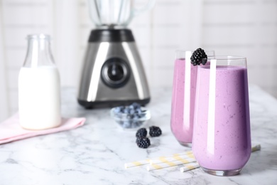 Photo of Tasty milk shakes and berries on white marble table