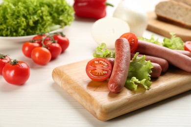 Photo of Delicious vegetarian sausages with lettuce and tomatoes on white wooden table
