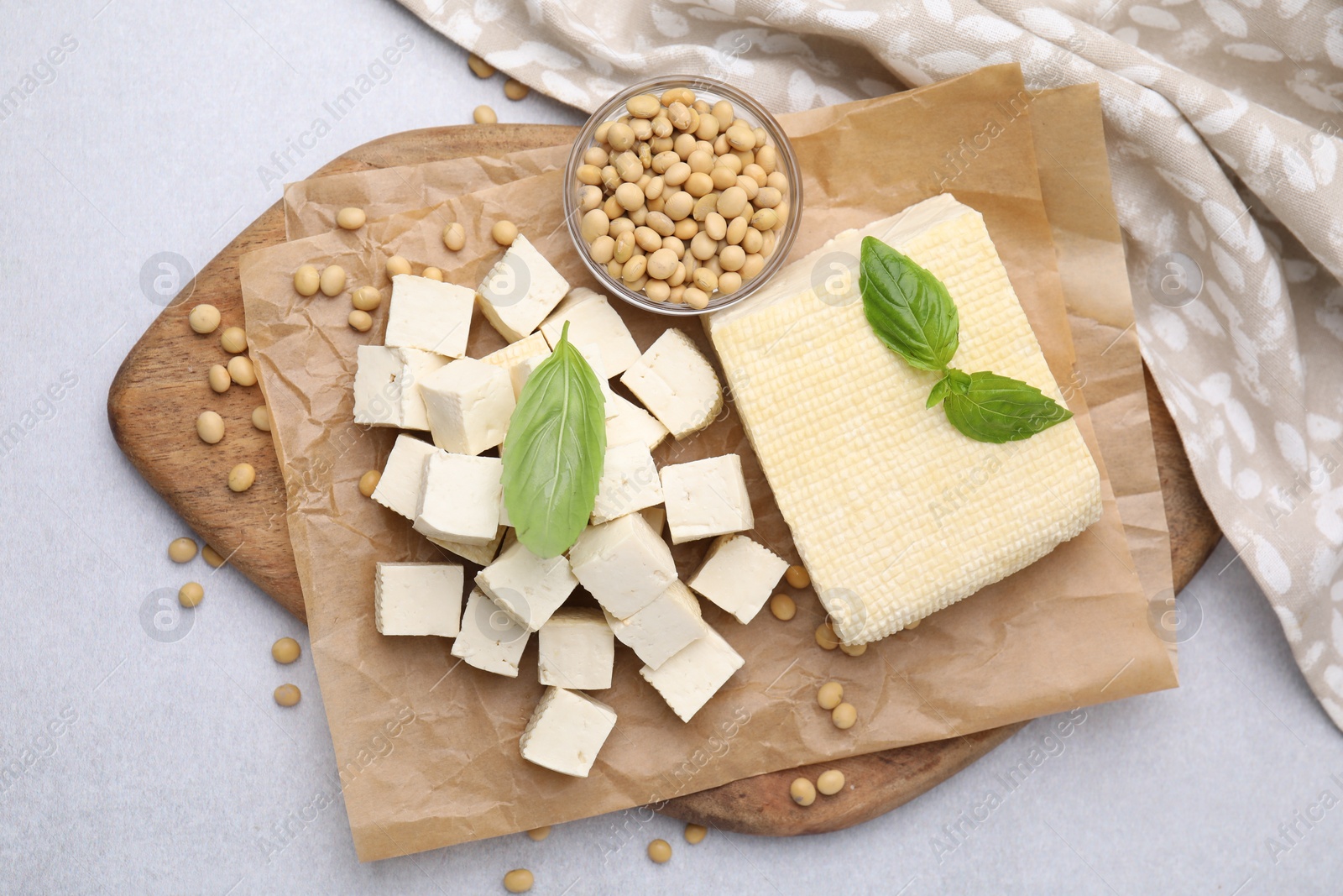 Photo of Delicious tofu cheese, basil and soybeans on light gray table, flat lay