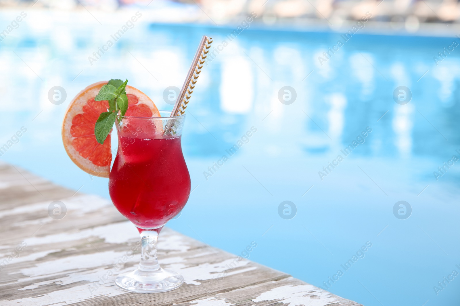 Photo of Refreshing cocktail near outdoor swimming pool on sunny day. Space for text