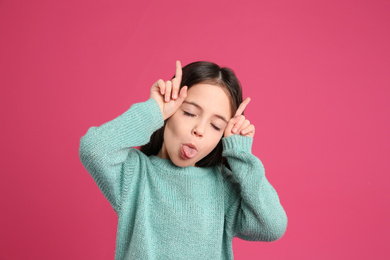 Portrait of cute little girl on pink background