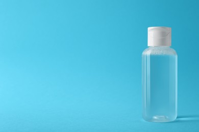 Photo of Bottle of micellar water on light blue background, space for text