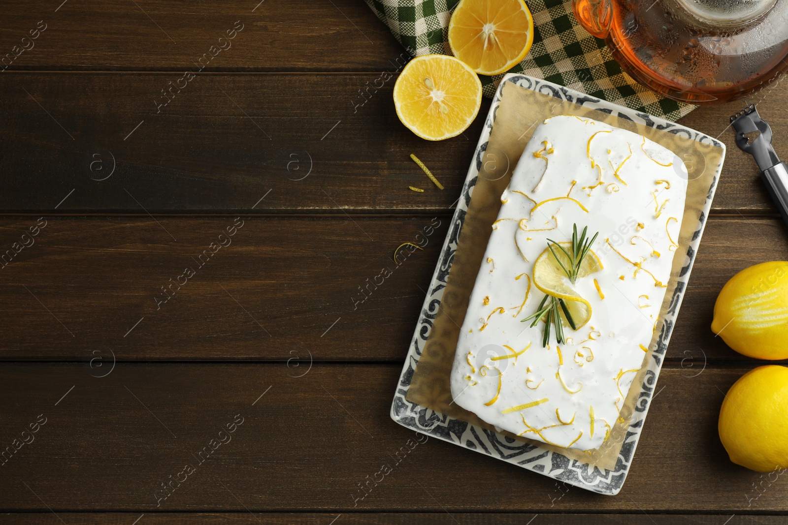 Photo of Tasty lemon cake with glaze and citrus fruits on wooden table, flat lay. Space for text