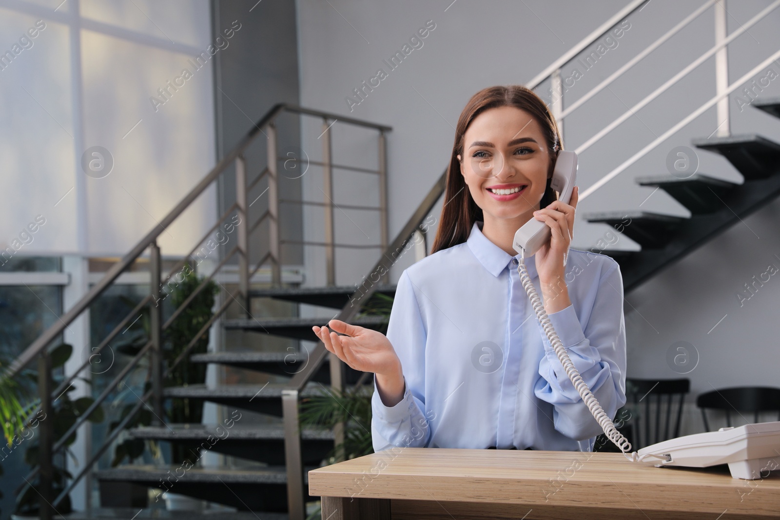 Photo of Female receptionist talking on phone at workplace. Space for text