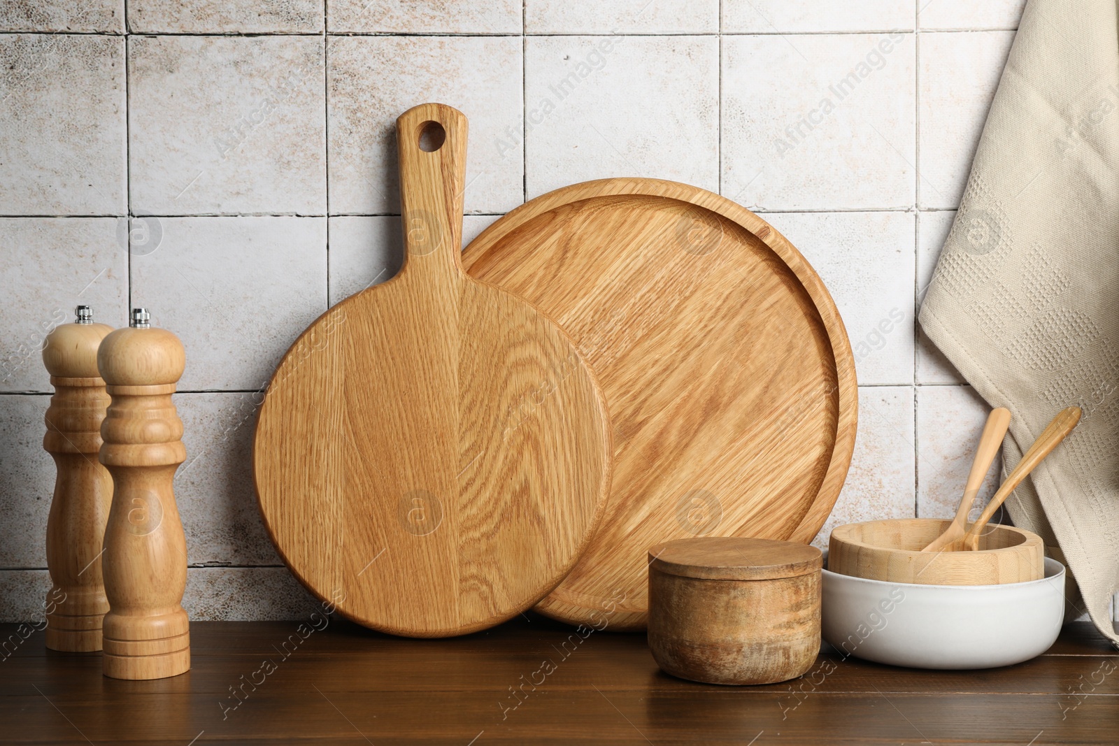 Photo of Wooden cutting boards and dishware on table near tiled wall