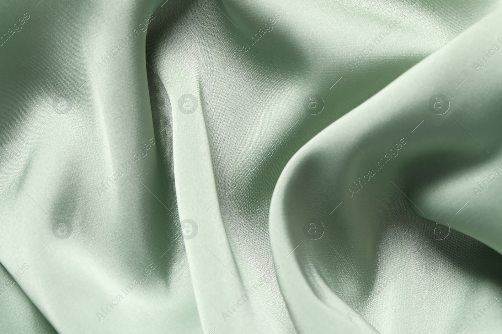 Photo of Texture of light green crumpled silk fabric as background, top view