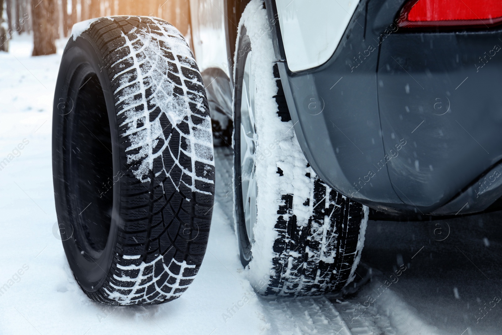 Image of Snow tire near car on road in winter, closeup