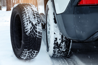 Image of Snow tire near car on road in winter, closeup
