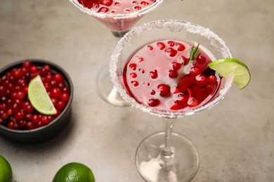 Photo of Tasty cranberry cocktail with rosemary and lime in glasses on grey table, closeup