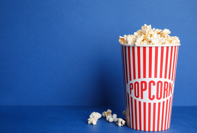 Photo of Tasty fresh pop corn on blue background, space for text