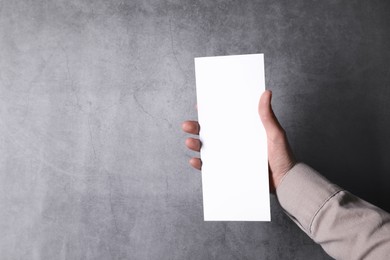 Photo of Man holding blank card at grey table, top view. Mockup for design
