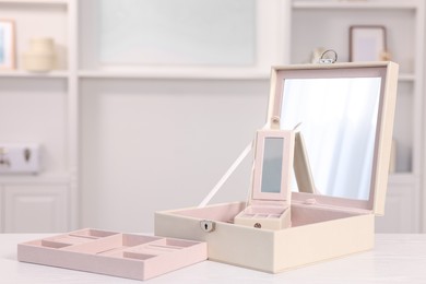 Photo of Empty jewelry box with mirror on white wooden table indoors