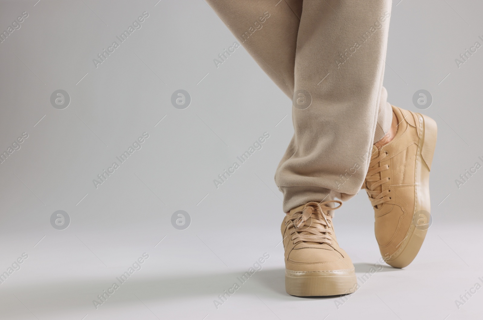 Photo of Man wearing stylish sneakers on light grey background, closeup. Space for text