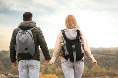 Photo of Couple of hikers with travel backpacks enjoying nature on autumn day, back view