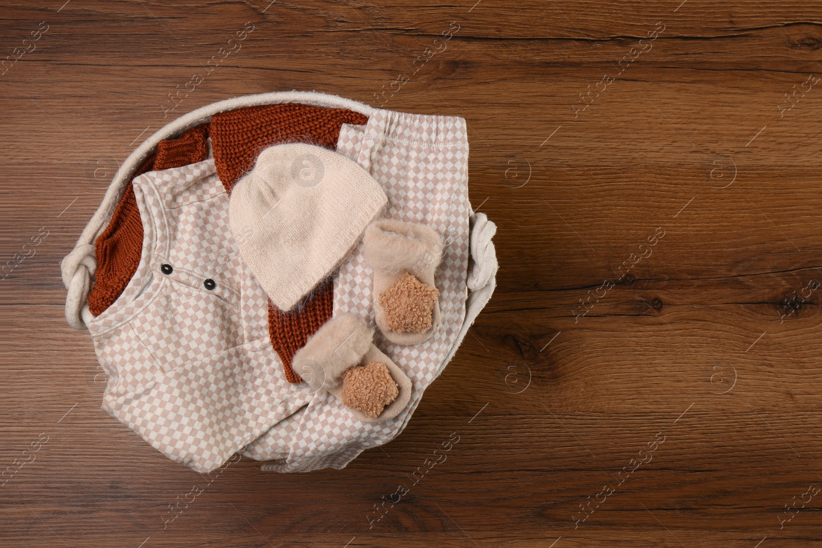 Photo of Laundry basket with baby clothes on wooden table, top view. Space for text