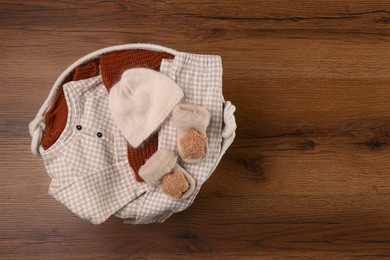 Photo of Laundry basket with baby clothes on wooden table, top view. Space for text