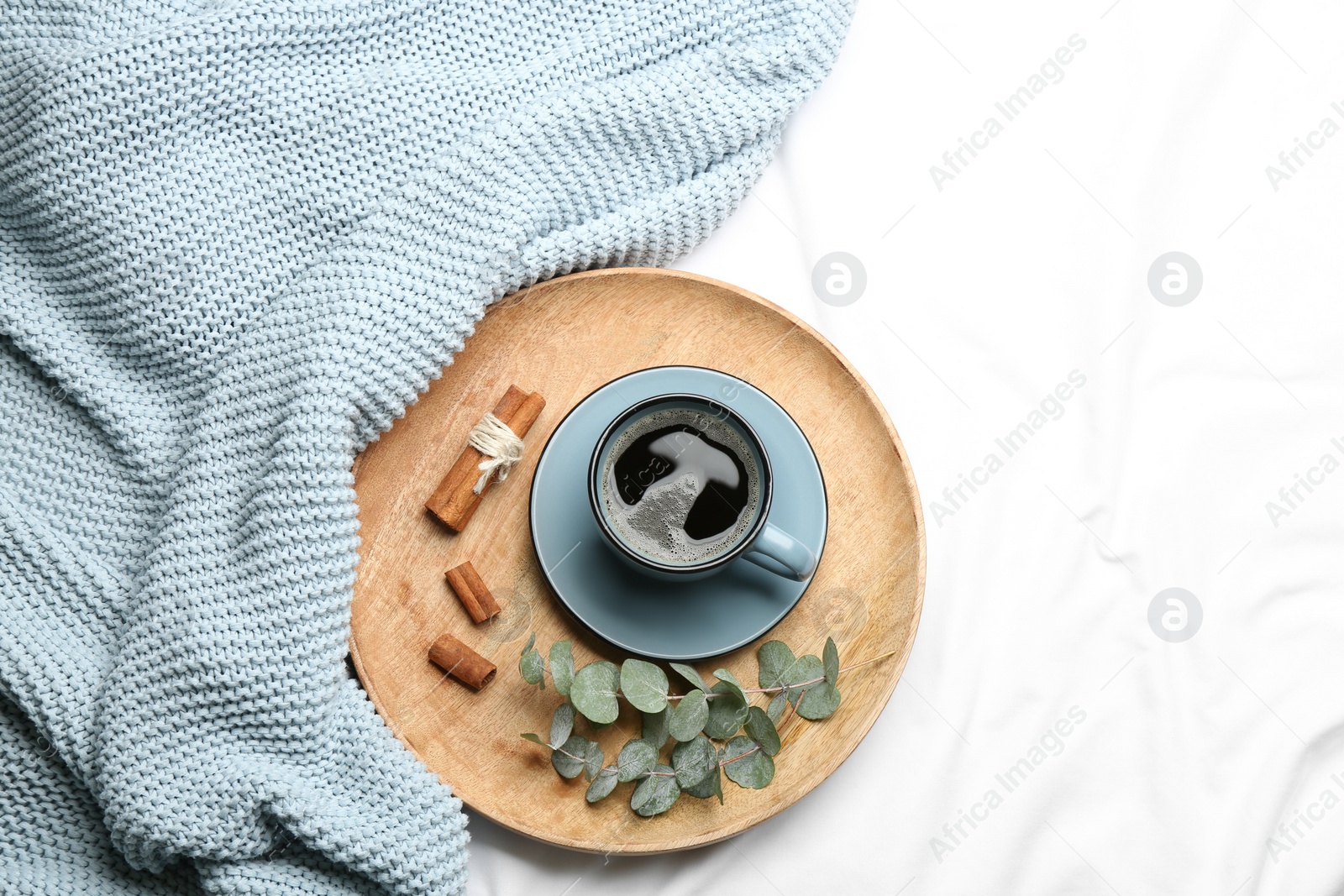 Photo of Flat lay composition with hot drink and warm plaid on white bedsheet