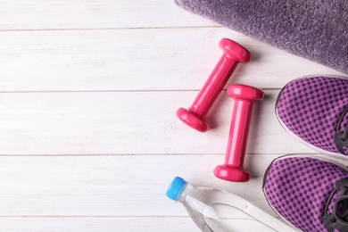 Flat lay composition with vinyl dumbbells, sneakers and space for text on wooden background