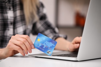 Photo of Woman with credit card using laptop for online shopping at white table, closeup