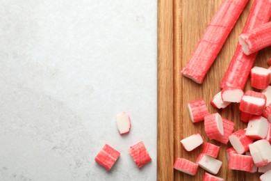 Photo of Cut crab sticks on light table, flat lay. Space for text