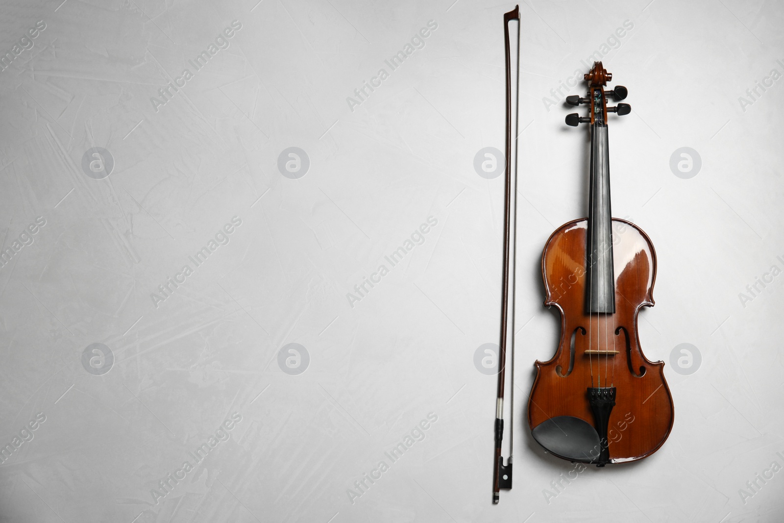 Photo of Beautiful violin and bow on grey stone table, flat lay. Space for text