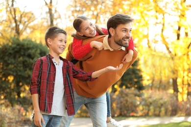 Photo of Happy father and children spending time in park. Autumn walk