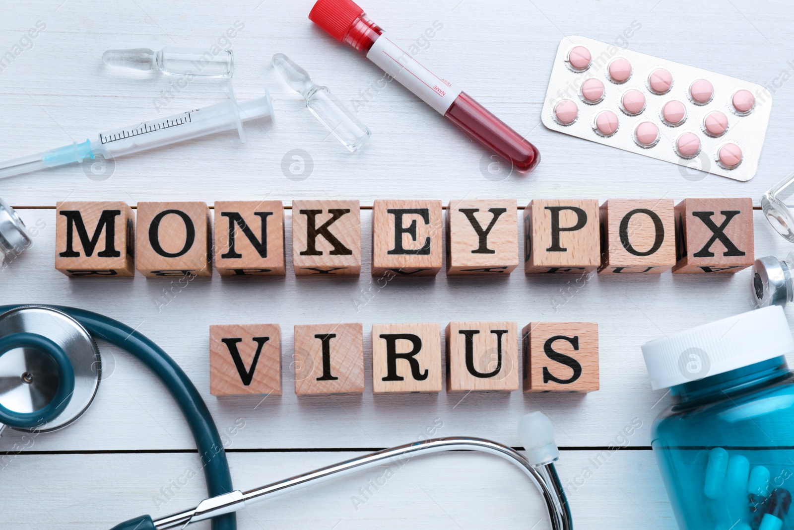 Photo of Flat lay composition with words Monkeypox Virus made of cubes and medical supplies on wooden white table