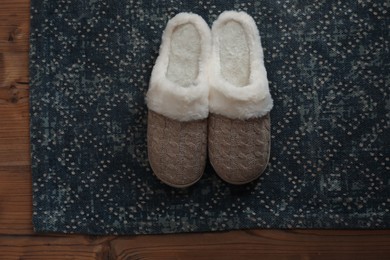 Photo of Stylish door mat and slippers on wooden floor, top view