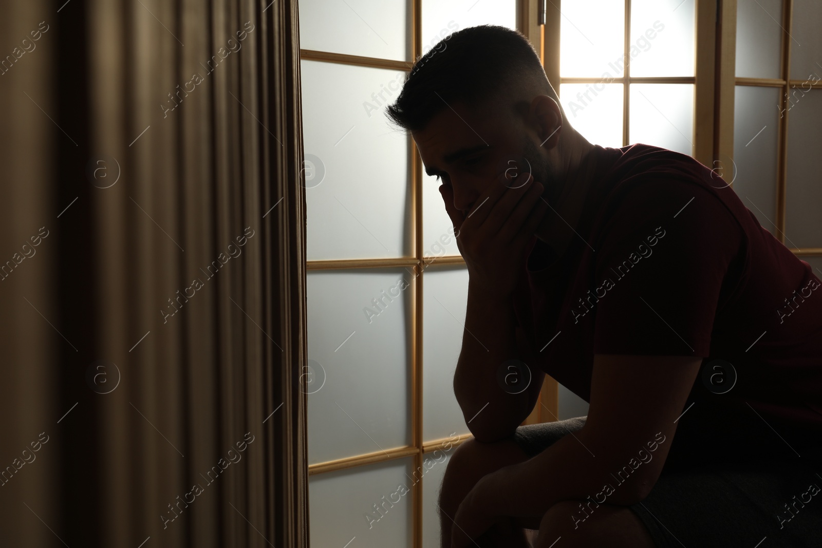 Photo of Silhouette of sad man at home. Space for text