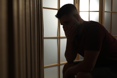 Photo of Silhouette of sad man at home. Space for text