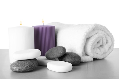 Photo of Towel, candles and spa stones on table against white background
