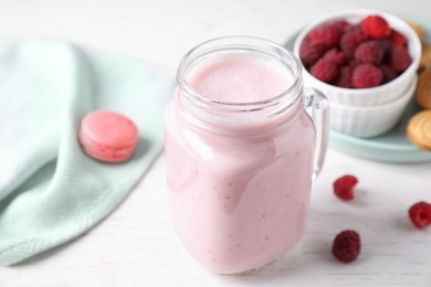 Tasty raspberry milk shake in mason jar on white wooden table