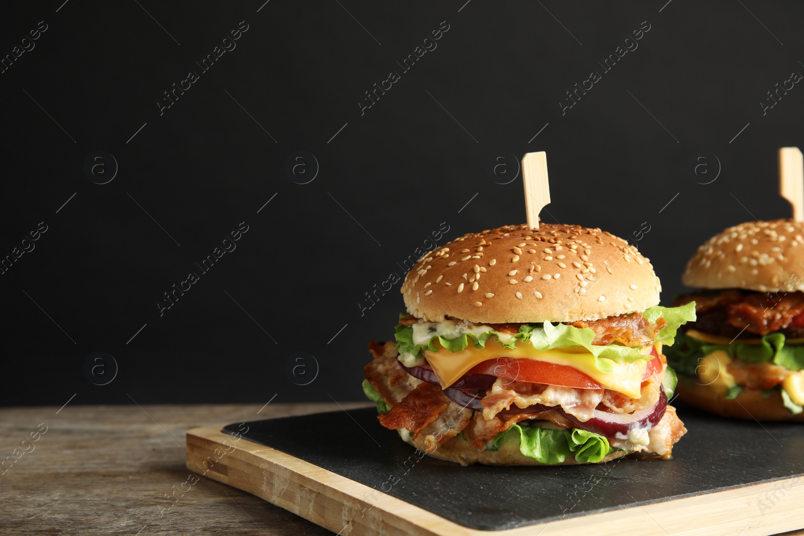 Photo of Tasty burger with bacon served on table. Space for text