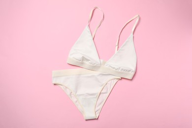 Photo of Stylish white women's underwear on pink background, flat lay
